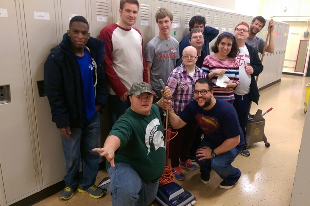 The custodial maintenance class in front of school lockers with cleaning supplies ready.