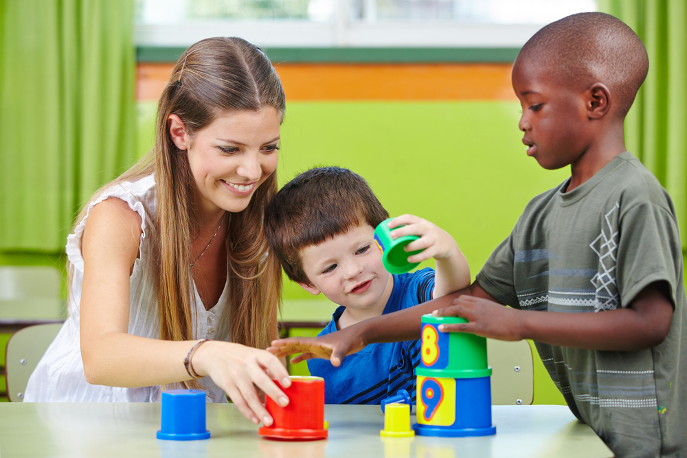 A therapist helping children stack cups.